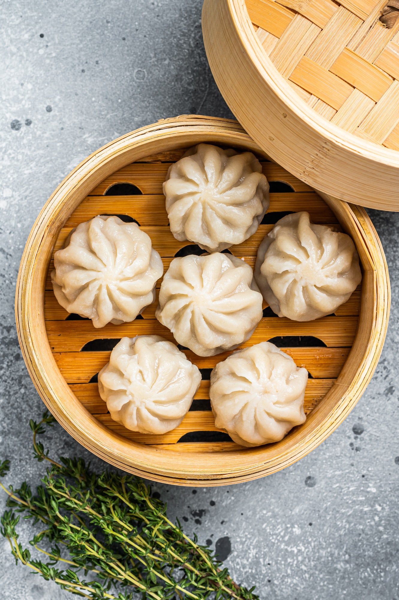 Steamed baozi dumplings stuffed with meat in a bamboo steamer. Gray background. Top view